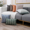 A collection of geometric jacquard lumbar pillow covers in shades of gray, orange, and teal displayed on a sofa.