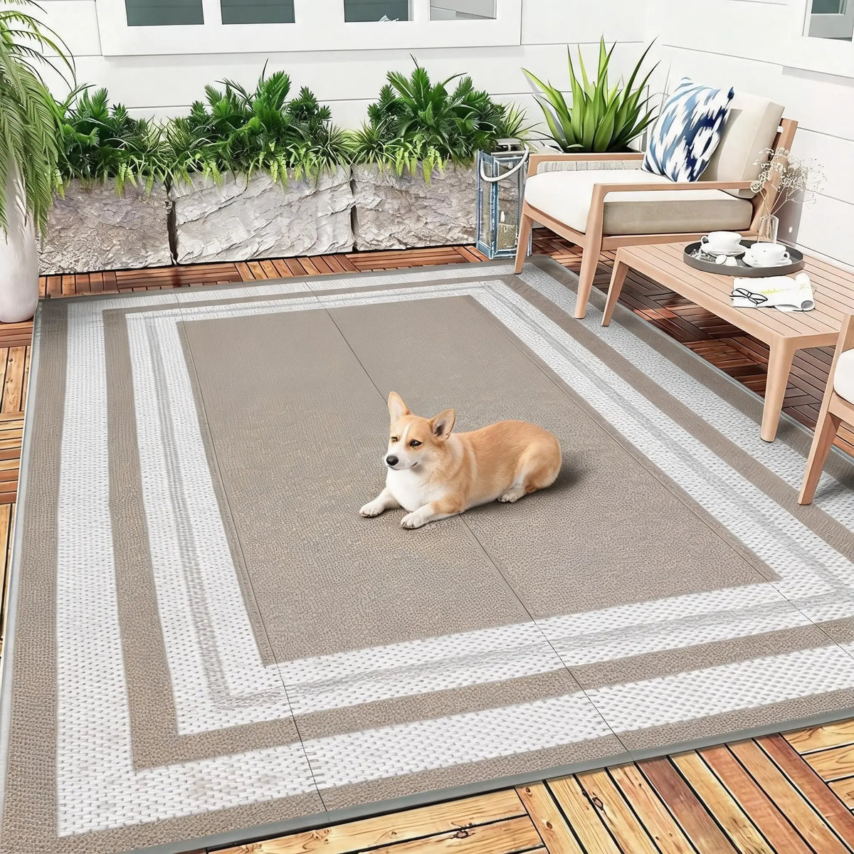 A light brown dog lies on a rectangular outdoor patio rug with gray and white stripes, set outdoors near a wooden table.