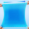 A bright blue honeycomb silicone seat cushion being held by hands, showing its mesh texture.