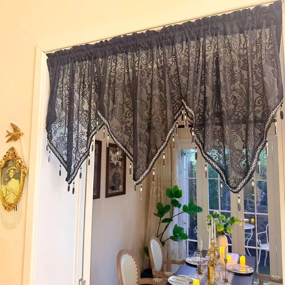 Elegant black lace curtain valance hanging over a window with sheer curtains and decorative elements.