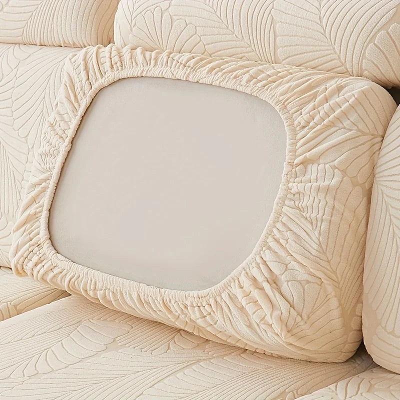 A beige luxury sofa slipcover featuring a textured leaf pattern and a square cushion.