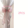 Two pink fabric ribbon bow curtain tiebacks shown in a vertical display.