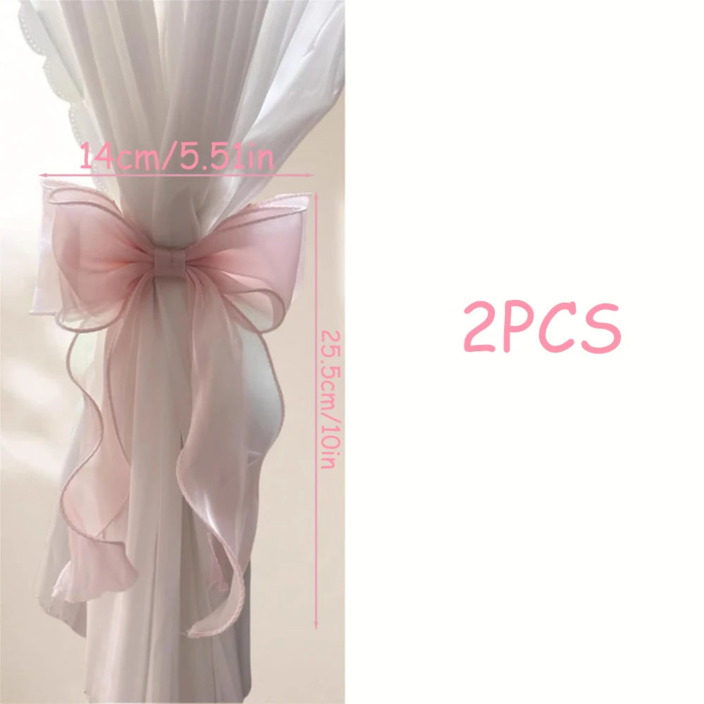 Two pink fabric ribbon bow curtain tiebacks shown in a vertical display.