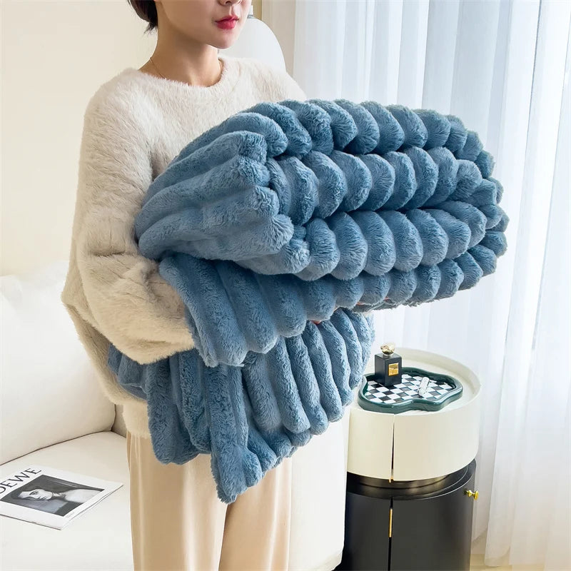 A fluffy blue plush winter blanket is draped over a person's arm in a bright indoor setting.