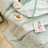 Light mint green floral embroidery quilt bedspread set with ruffled edges and a fluffy cream pillow.