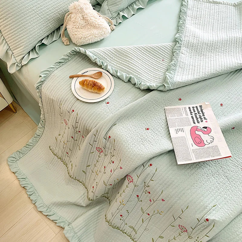 Light mint green floral embroidery quilt bedspread set with ruffled edges and a fluffy cream pillow.