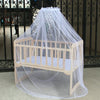 A wooden crib or bed covered by a sheer white mosquito net for protection.