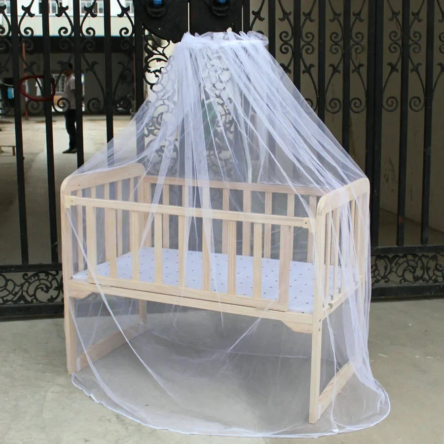 A wooden crib or bed covered by a sheer white mosquito net for protection.