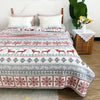 A red and white embroidered cotton quilted bedspread with deer motifs on a bed.