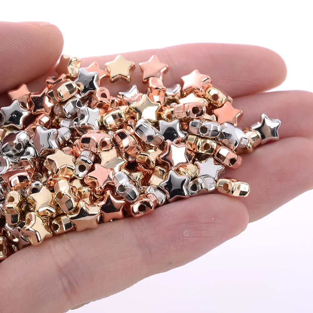 A handful of mixed gold silver and rose gold star-shaped acrylic beads for jewelry making