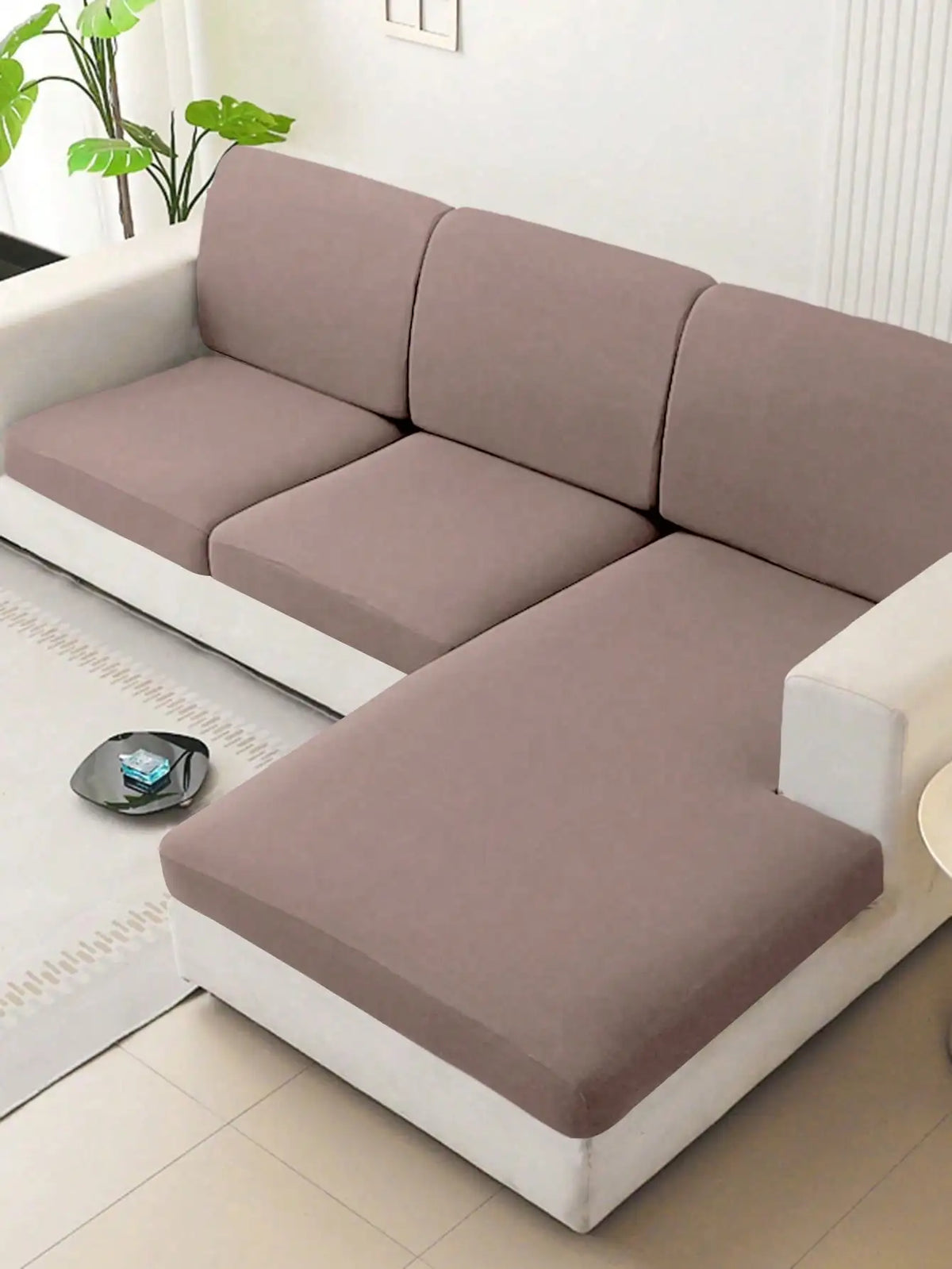 A modern, light beige sofa with a slipcover featuring soft cushions and white trim in a bright room.