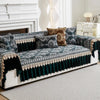 A dark teal quilted sofa cover with patterned fabric and gold trim displayed on a white sofa.