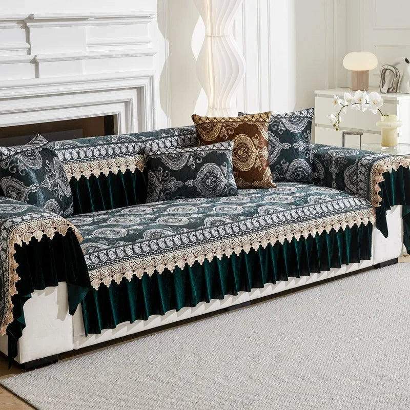 A dark teal quilted sofa cover with patterned fabric and gold trim displayed on a white sofa.