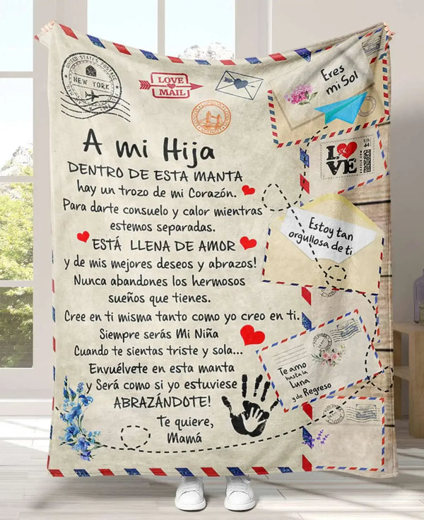 A knitted blanket featuring a heartfelt message in Spanish for a daughter