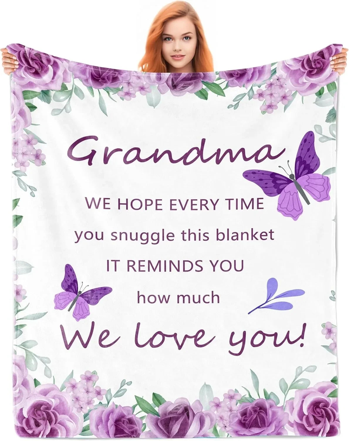 A woman in a pink top holds a white blanket featuring a floral design and the text We hope every time you snuggle this blanke
