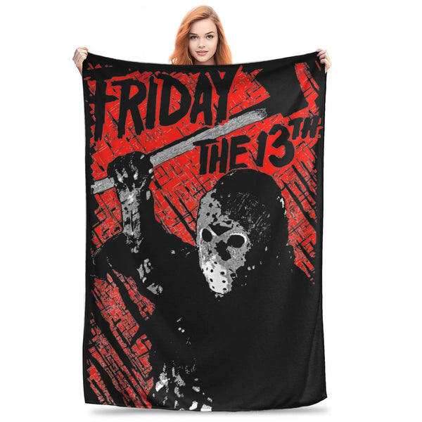 A woman holds up a black fleece throw blanket featuring a distressed design with the text Friday the 13th and a skull.