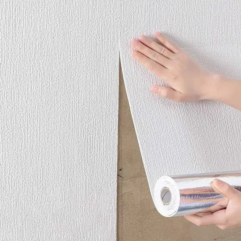 A hand is peeling a sheet of self-adhesive 3D thermal insulation wallpaper with a linen texture from a roll.