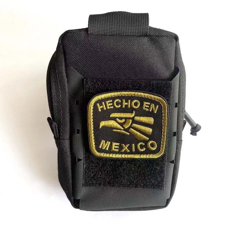 Black tactical pouch with a gold embroidered patch featuring the text HECHO EN MEXICO and an eagle design.
