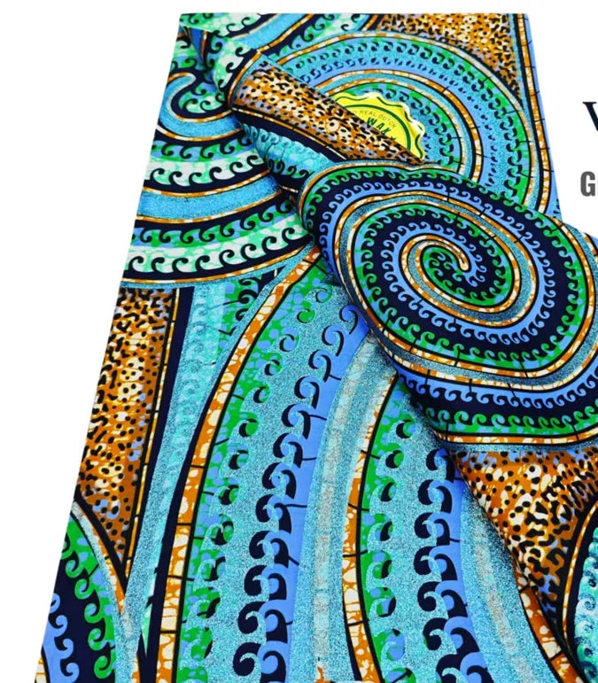 Close-up of an African wax print fabric featuring swirling patterns in teal, green, orange, and black.