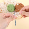 A pair of bent tip tapestry needles is shown being used to thread a green yarn onto a piece of twine.