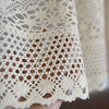 Close-up of a rustic crochet half curtain with linen weave in beige color.