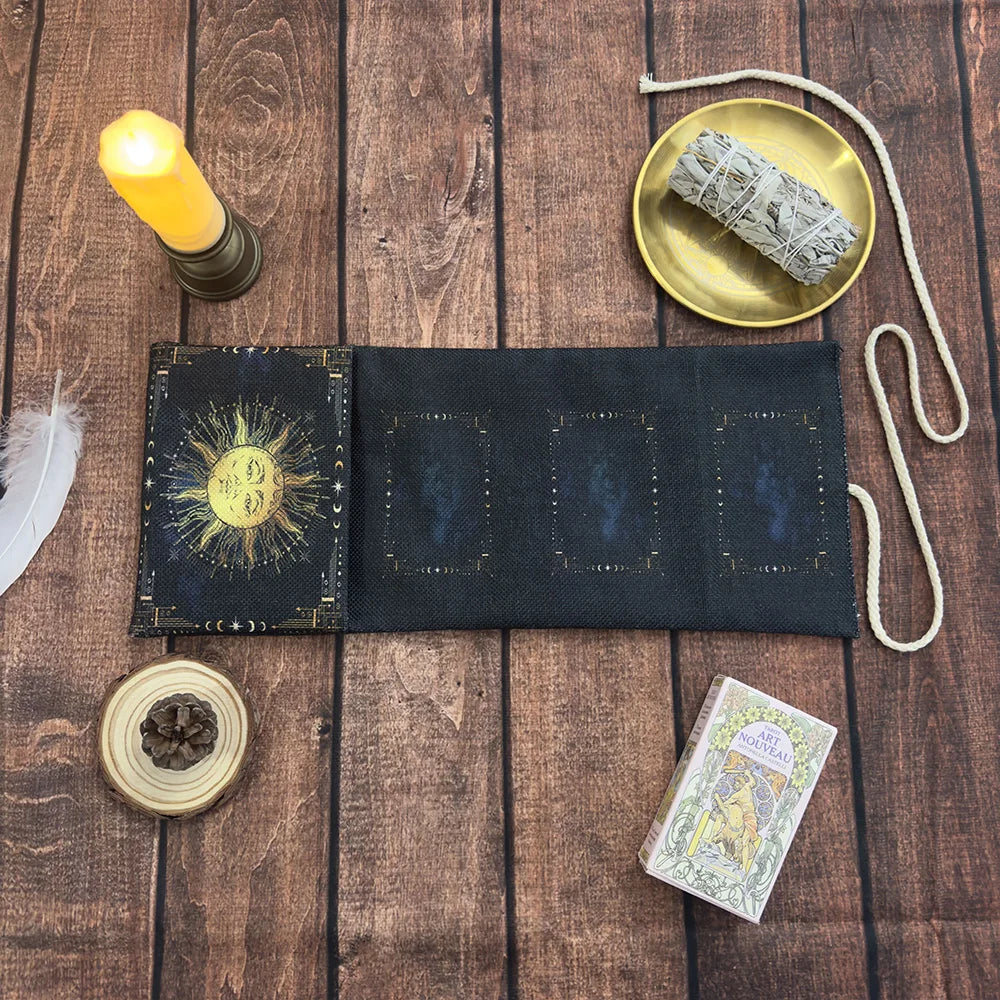 A dark blue tarot card storage pouch with a sun design, next to a golden plate and a candle.