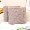 A fluffy, taupe velvet throw pillow cover is displayed on a white surface.