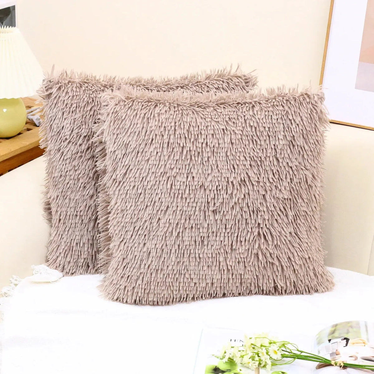 A fluffy, taupe velvet throw pillow cover is displayed on a white surface.