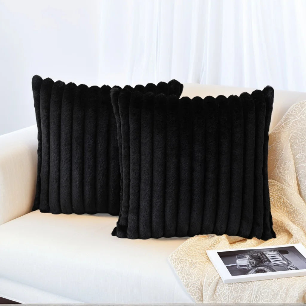 A set of two black, ribbed decorative pillowcases resting on a light-colored sofa.