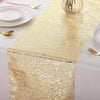Metallic gold table runner with a textured pattern set on a white tablecloth, featuring gold cutlery and glassware.