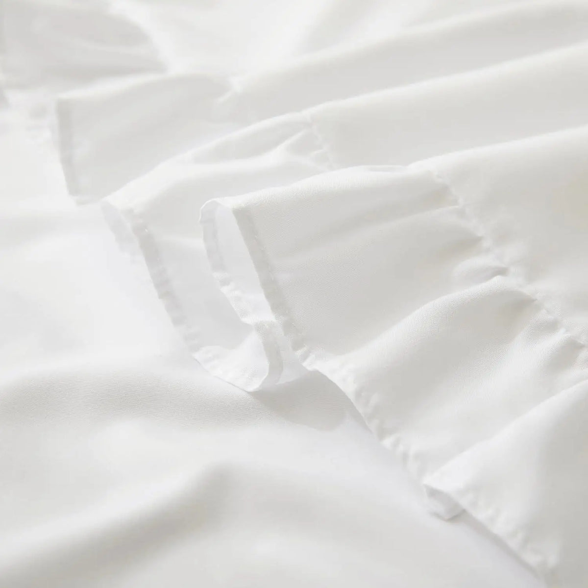 White ruffled envelope closure pillow covers laid out on a white surface.