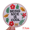 Round embroidered patch with a pink background featuring the text BEING NICE IS COOL surrounded by green and yellow leaves.