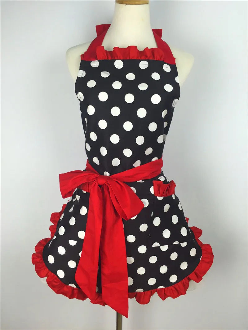 A black polka dot ruffle apron with red trim tied in a bow displayed on a mannequin.