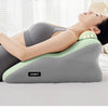 A woman is lying on an ergonomic prostrate pillow for stomach sleepers, which is gray and light green.
