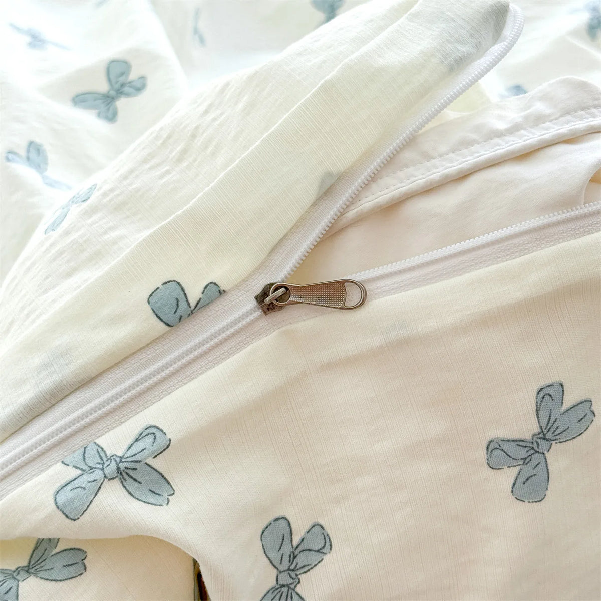 Close-up of a white microfiber duvet cover with light blue floral butterfly patterns and a silver zipper.