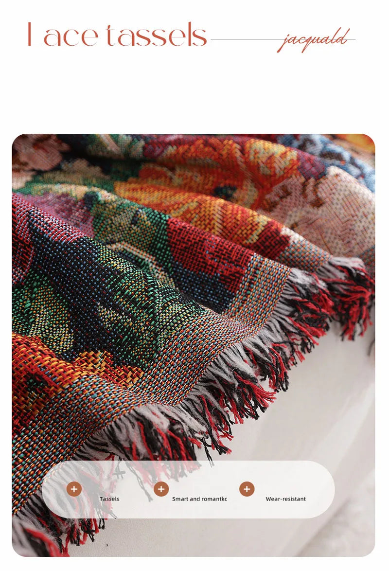 A close-up of a richly colored floral jacquard tasseled sofa throw blanket with fringed edges.