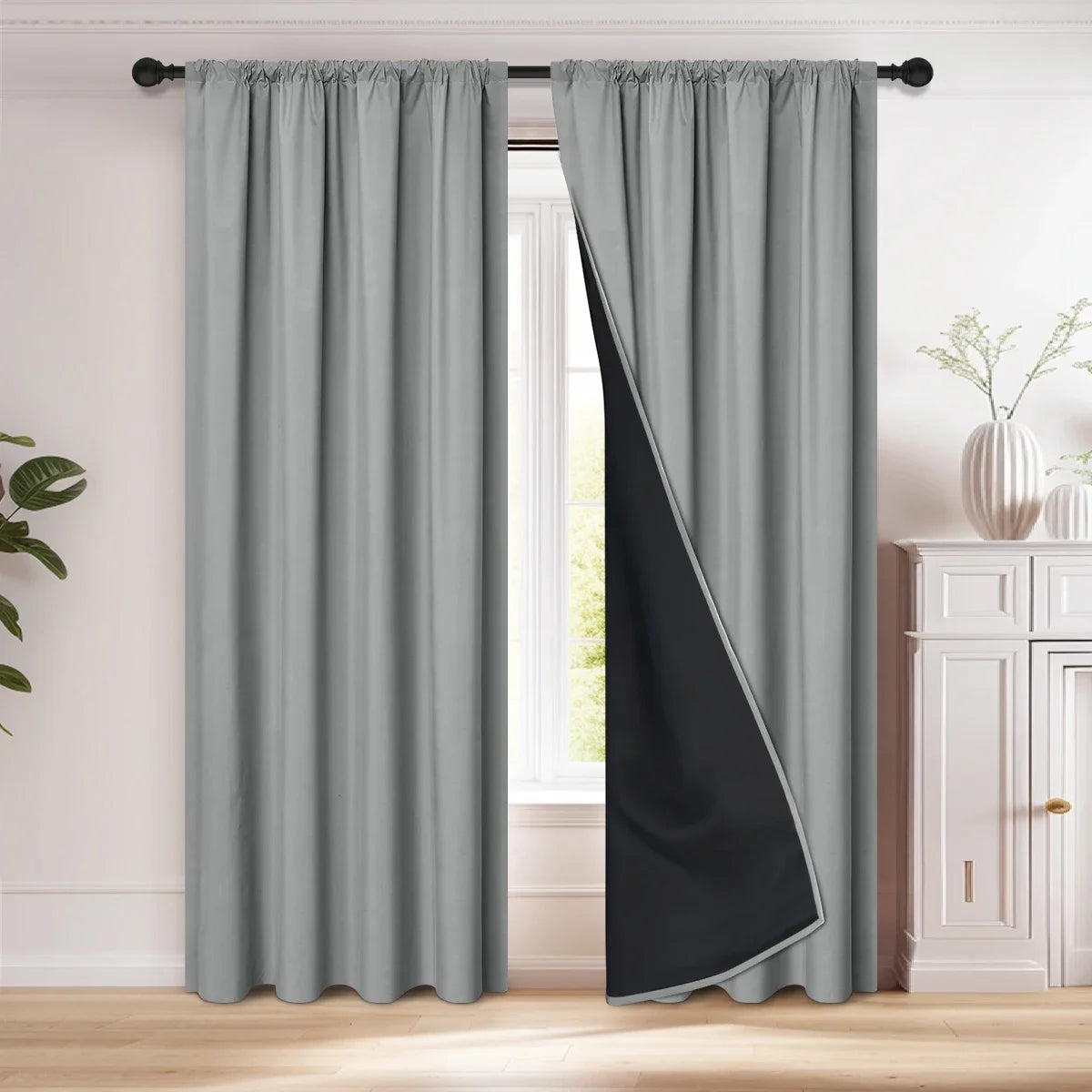 Gray blackout curtain with a black diagonal panel hanging in a window frame.