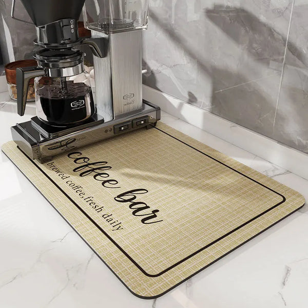 A silver coffee grinder and glass carafe sit on a beige mat labeled brewed coffee fresh daily.