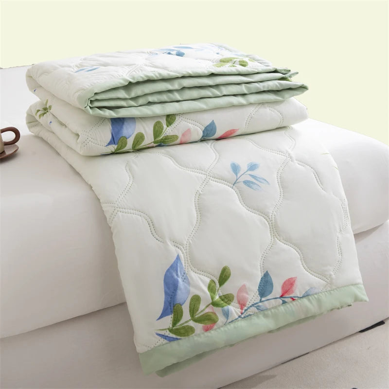 A stack of white quilted duvet covers featuring light blue and green floral embroidery.