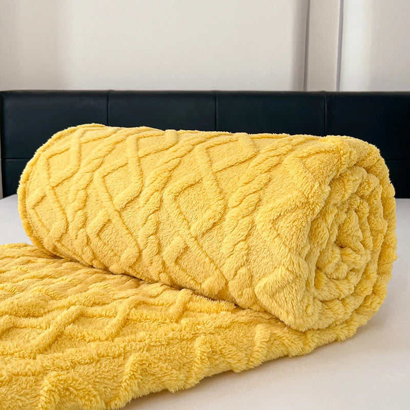 A rolled yellow ultra-soft coral fleece blanket resting on a white surface.