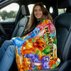A young woman is sitting in a car, holding a colorful blanket featuring cartoon dinosaurs.
