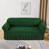A deep emerald green stretch knit sofa cover with a bubble lattice texture displayed indoors.