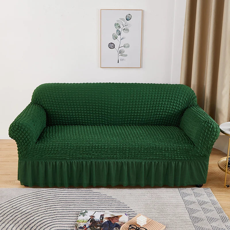 A deep emerald green stretch knit sofa cover with a bubble lattice texture displayed indoors.