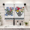 A set of checkered kitchen towels hanging on a rack above a kitchen sink.