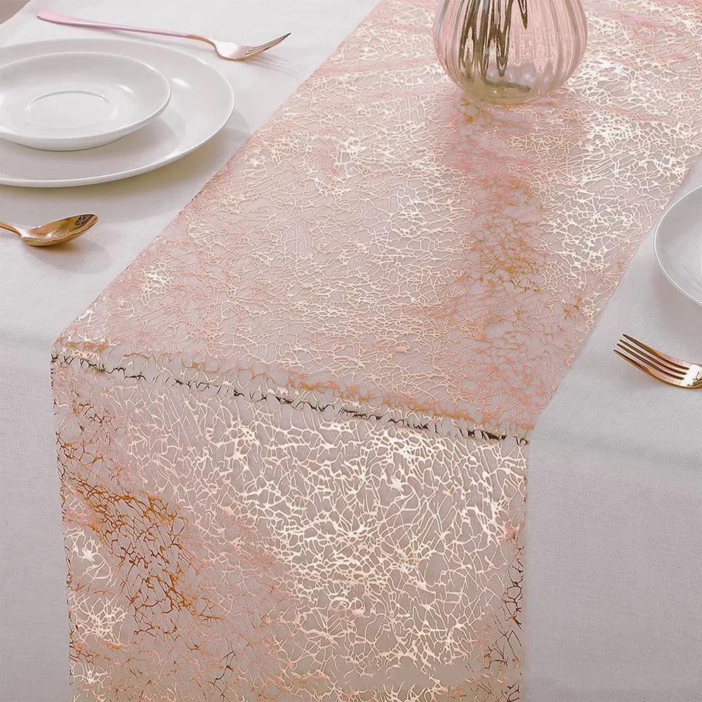A pink metallic gold table runner displayed on a white tablecloth with tableware and a glass vase.