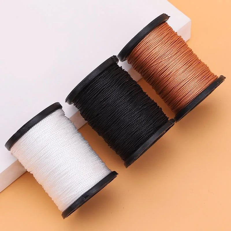 Three spools of heavy duty nylon upholstery thread in white, black, and brown on a light background.