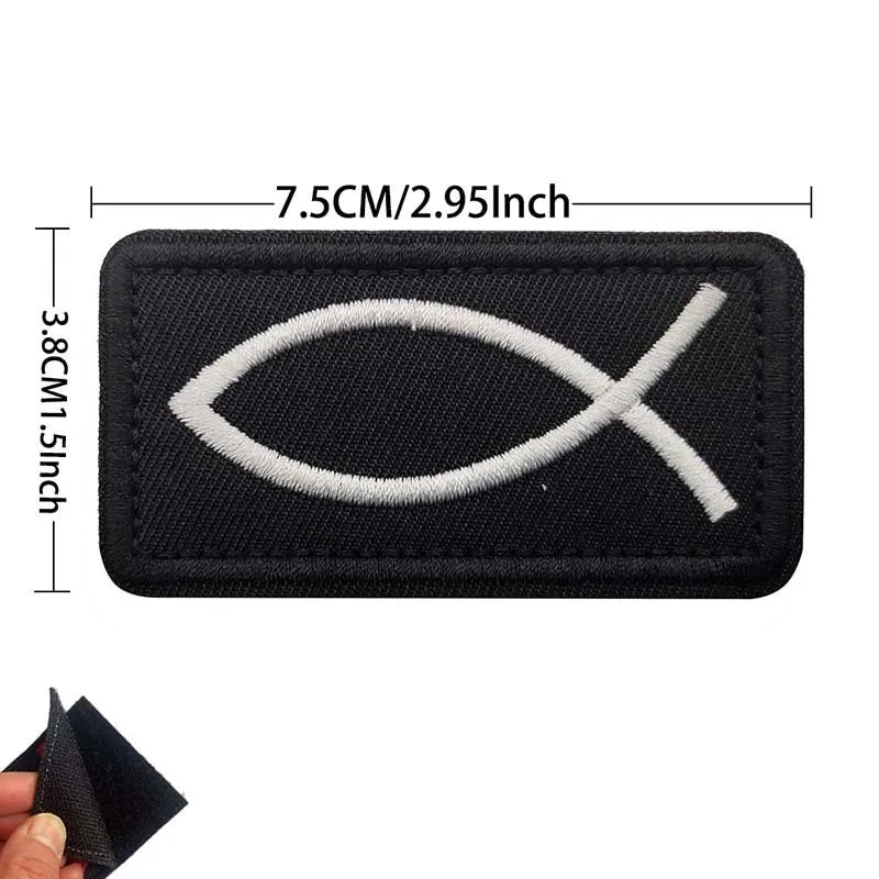 Black embroidered patch featuring a white cross design with dimensions 7.5cm/2.95Inch by 3.8cm/1.5inch.