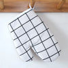 A pair of white oven gloves with a black grid pattern hanging on a wooden rack.