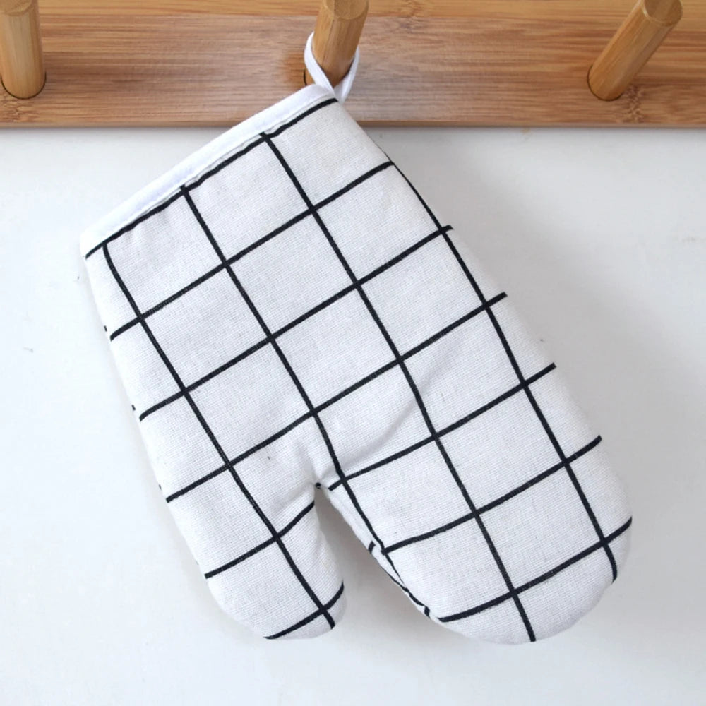 A pair of white oven gloves with a black grid pattern hanging on a wooden rack.