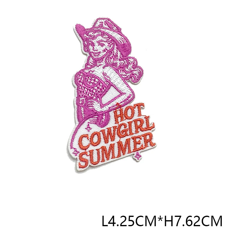 A pink embroidered patch featuring a woman with long purple hair and the text HOT COW GIRL SUMMER